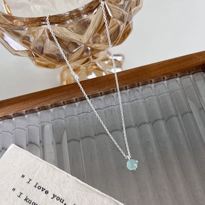 Détail d'un collier en argent avec pendentif rond en cristal vert clair sur un plateau