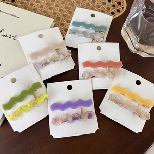 Set of wavy acetate hair clips in various colors displayed on a wooden surface