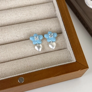 Détail de boucles d'oreilles fleurs bleues avec zircon et pendentifs cœur argent