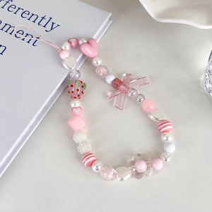 Detailed macro view of pink strawberry beaded phone strap with heart and bow charms