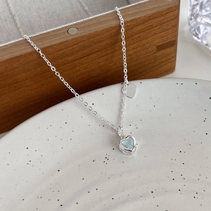 Dettaglio della collana con pendente a cuore in zircone blu su un piatto di ceramica