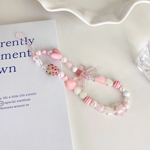 Detailed close-up of pink beaded phone charm with strawberry and heart accents