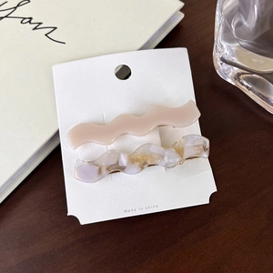 Detail of wavy acetate hair clips in beige and purple marble with gold glitter