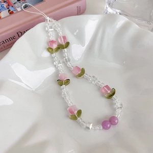 Détail d'une lanière de téléphone en perles de tulipe rose sur plateau en céramique