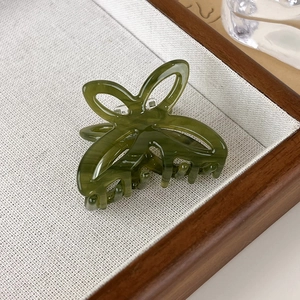 Detail of a dark green acetate butterfly hair claw clip with marble texture on a tray