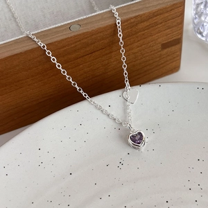 Dettaglio macro di una collana in argento con ciondolo a forma di cuore in zircone viola
