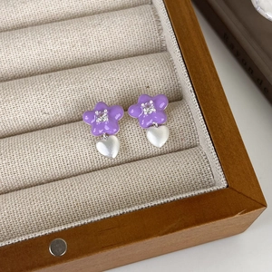 Gros plan de boucles d'oreilles fleurs mauves avec pendentifs cœurs et zircon brillant