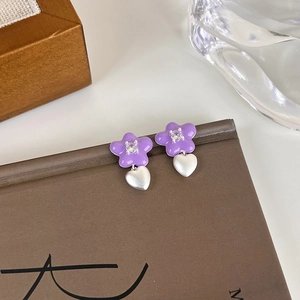 Vue détaillée d'une boucle d'oreille fleur violette avec pendentif cœur sur livre