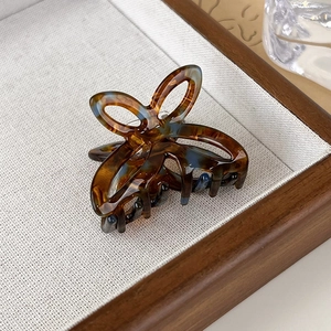 Detail view of small acetate butterfly hair claw with blue tortoise shell pattern on tray