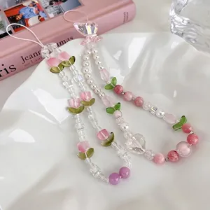 Bijou de téléphone fait main avec tulipes roses, perles et cœurs sur plateau blanc