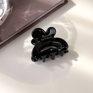 Détail de la pince à cheveux en résine noire avec logo doré Barrette la France au soleil