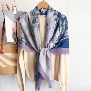 Detail of artistic floral print scarf with soft frayed edges on white knitwear