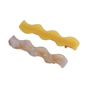 Set of two wavy acetate hair clips in mustard yellow and white marble texture patterns