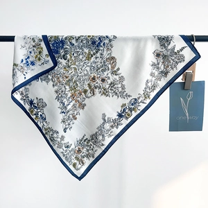 French vintage floral square scarf with navy blue edges hanging on a metal rod
