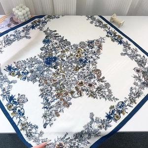Detail of a large square silk scarf featuring floral star patterns and elegant blue borders
