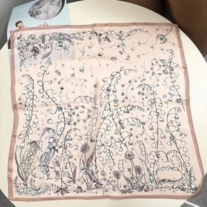 Flat lay of pink silk scarf with floral botanical prints and brown border on a round table