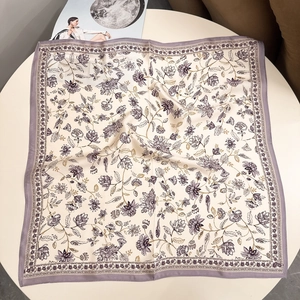 Close-up of premium silk scarf with elegant purple floral patterns and golden leaves