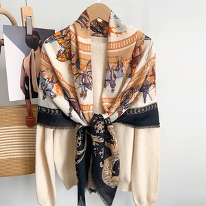 Close-up of luxury horse pattern scarf with fringe edges and warm orange beige tones