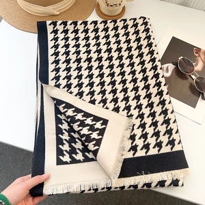 Close-up of black and white houndstooth scarf with fine tassel details on a white desk