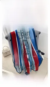 Detail view of red and blue retro striped silk scarf draped on a chair for fashion styling