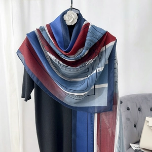 Detail of color-block scarf with elegant geometric patterns draped over a black sweater