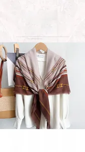 Detail of elegant chain print square scarf draped on a shirt with soft fringe edges