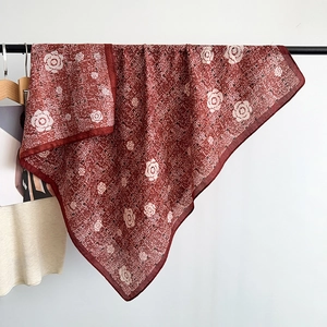 Detail of dark red camellia print scarf with fine grid texture hanging on a black rack