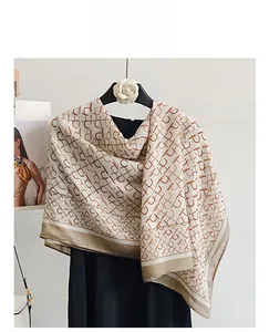 Detail of elegant beige long scarf with letter P pattern and orange contrast edges