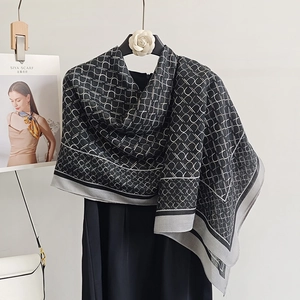 Elegant geometric print scarf shawl in black and grey hanging on a boutique hanger