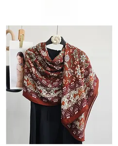 Detail of vintage paisley long scarf in brick red with ethnic floral patterns and drape