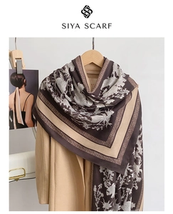 Detail of floral patterns on a dark brown scarf paired with a camel wool coat