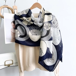 Detail of camellia floral print on a long cotton linen shawl draped over a beige sweater