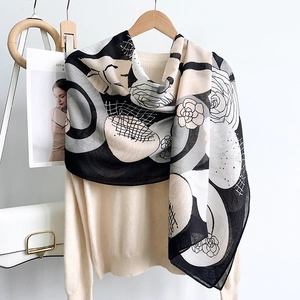 Elegant camellia and geometric print cotton linen scarf draped on a chic sweater