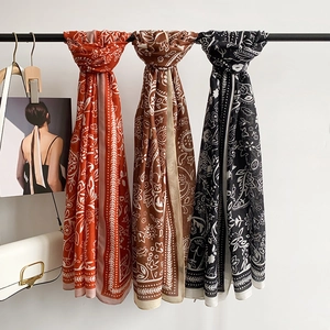 Bufanda étnica con estampado paisley naranja y marrón colgada con un bolso blanco