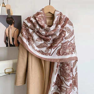 Floral print cotton linen scarf in beige and brown draped over a stylish winter coat