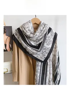 Detailed view of long cotton linen scarf with elegant black bamboo print on a beige coat