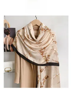 Detailaufnahme des Schals mit Blattmuster und braunem Rand an einem Camel-Mantel