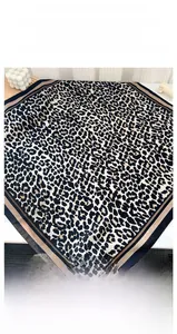 Close-up of leopard print silk scarf with striped borders on a decorative surface