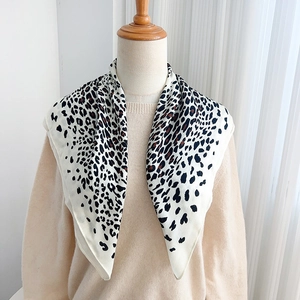Detail view of stylish leopard print silk scarf styled on a mannequin with beige knitwear