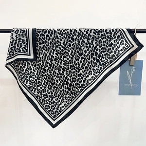 Detail of leopard print silk scarf with black and white striped border on a display rack