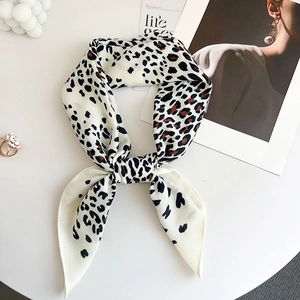 Detail of leopard print silk scarf tied in a stylish knot on a white minimalist background