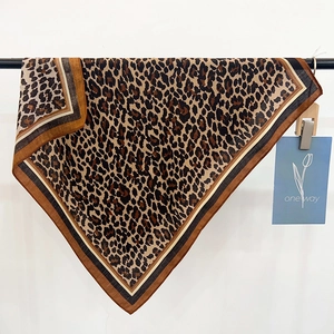 Chic leopard print square scarf with striped border hanging on a display rod