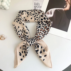 Detail of a knotted leopard print silk scarf on a white background with fashion accessories