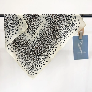 Fashionable leopard print square silk scarf for women in cream and brown hung on a rack