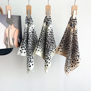 Chic leopard print silk scarves in white and caramel tones displayed on wooden hangers