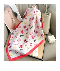 Detail of silk scarf with starfish and seashell prints draped on a designer handbag