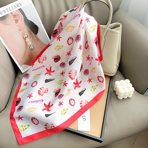Detail of silk-like square scarf with red ocean print draped on a beige handbag