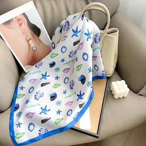 Detailed pattern of ocean starfish and seashells on silk scarf wrapped on a beige handbag