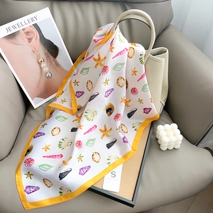 Detail of silk scarf with colorful starfish print draped on a handbag in a stylish setting