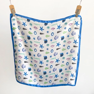 Detail of white silk scarf featuring blue marine patterns like starfish and seashells